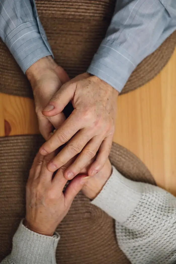 Close-up of elderly hands holding each other, symbolizing love and support.